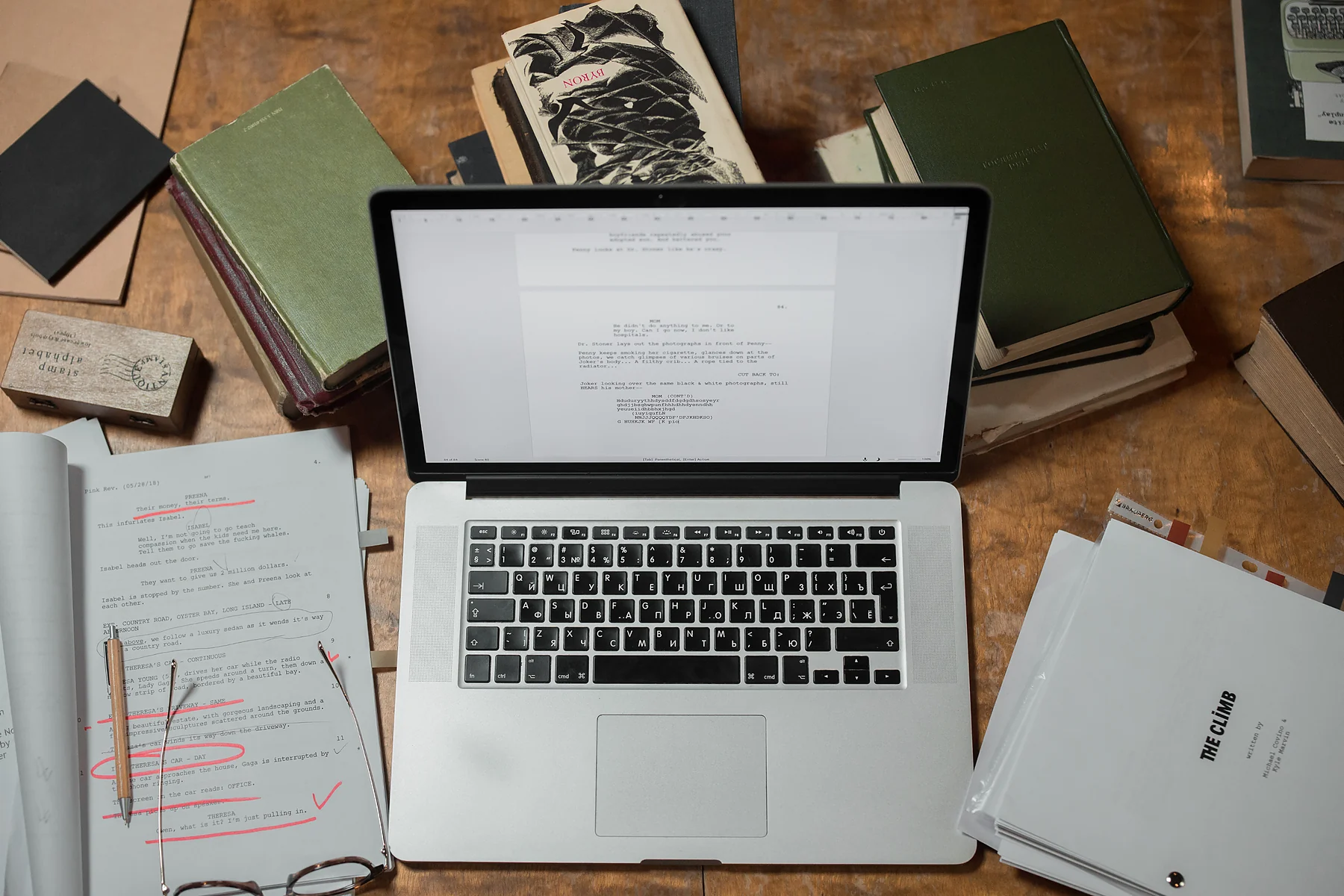 Laptop zwischen Büchern, Dokumenten und Notizen bei der Überarbeitung eines wissenschaftlichen Textes.